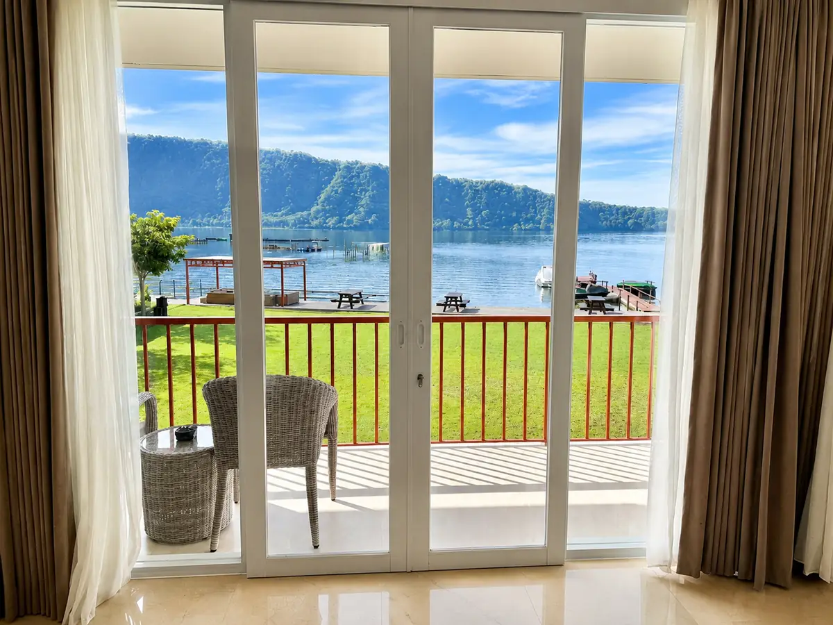 King Room with lake view: glass balcony doors opening to Lake Buyan and green hills.
