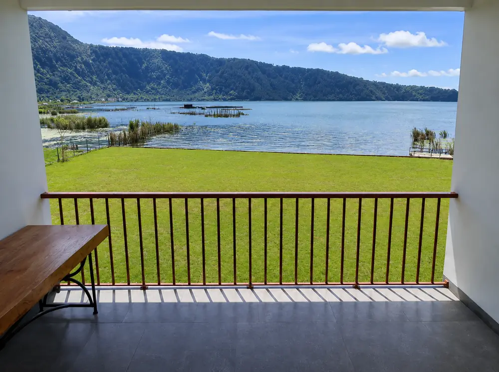 Private balcony with lawn, railing and a wide view over Lake Buyan and forested hills.