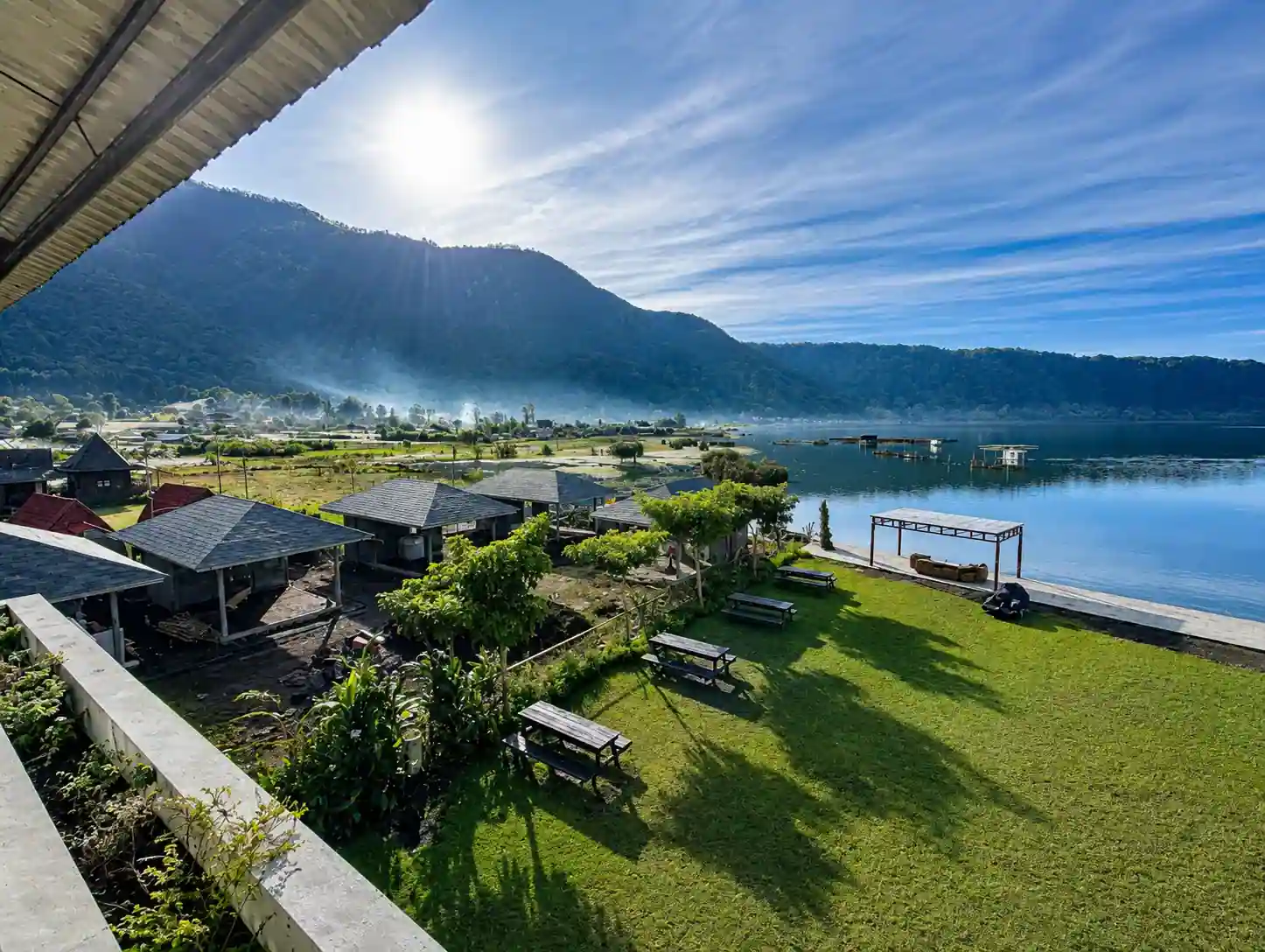 Timber picnic shelters and lawn on the Rusa by The Lake grounds above Lake Buyan.