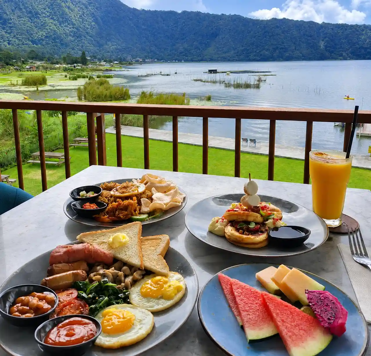 Breakfast plates and fresh juice on a balcony table overlooking Lake Buyan.