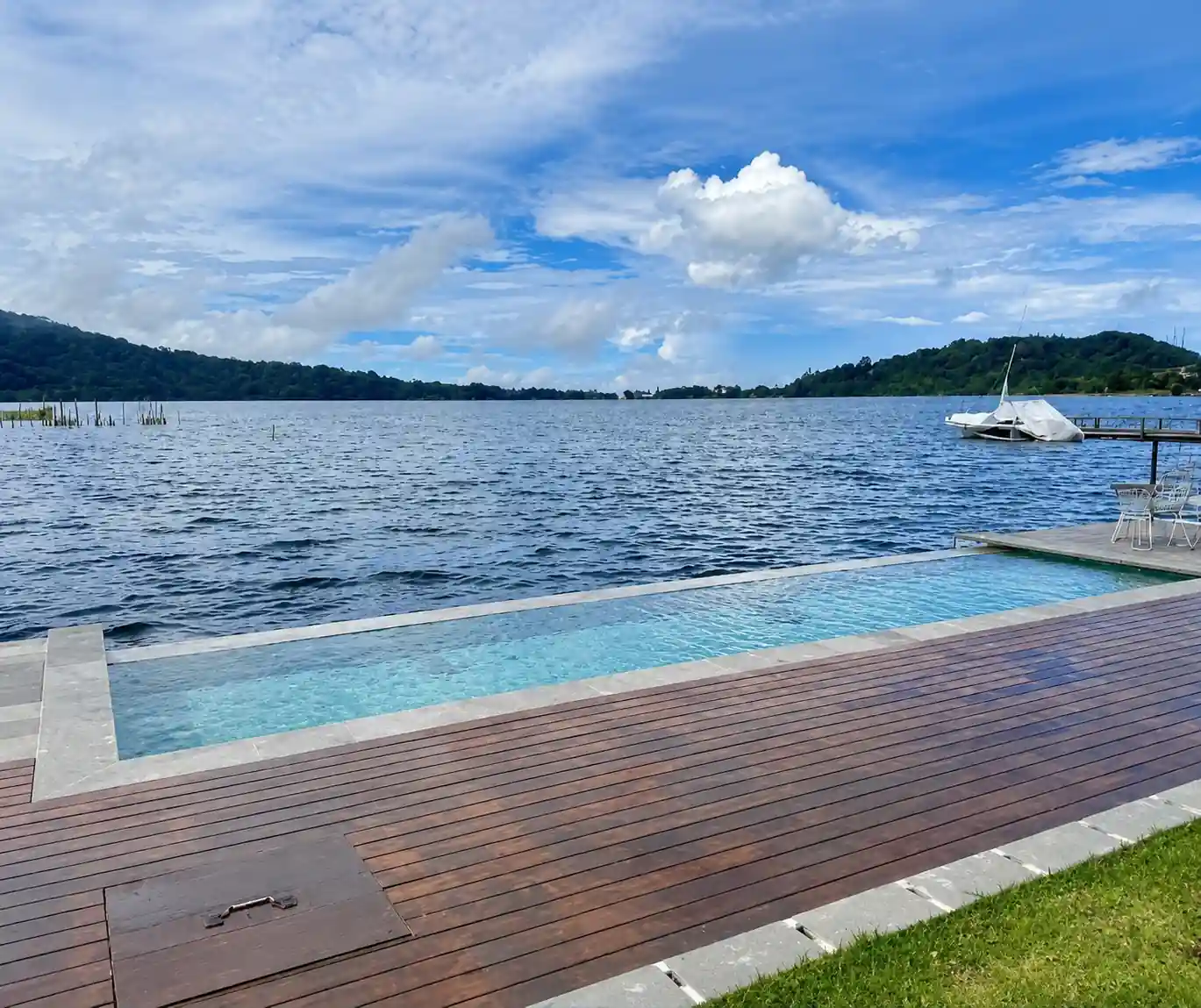 Outdoor pool and timber deck at the edge of Lake Buyan under a bright sky.